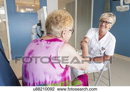 Stock Image - Female patient shaking hands with doctor. Fotosearch