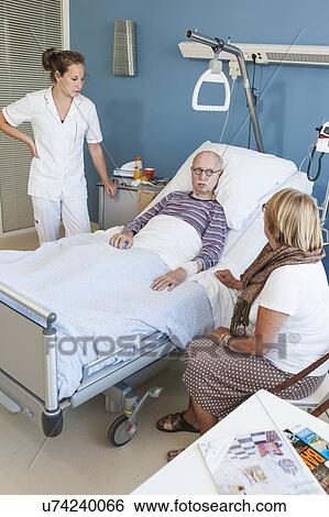 Stock Photograph - Female visitor and nurse talking to senior man. Fotosearch