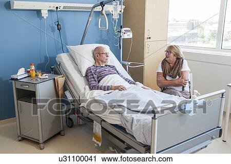 Stock Image - Female visitor listening to senior man. Fotosearch