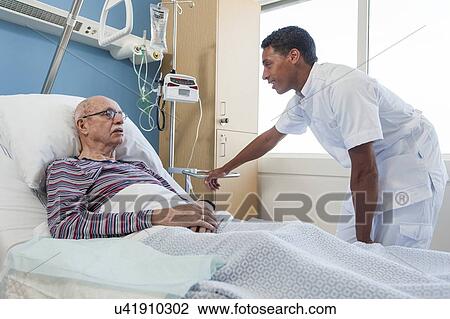Stock Image - Male nurse talking to senior man. Fotosearch