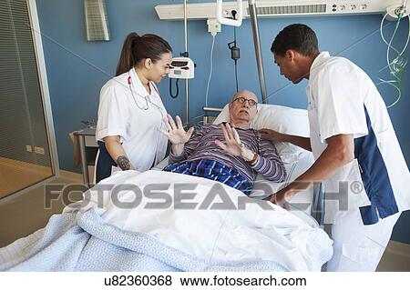 Stock Photo - Male patient in distress with two nurses. Fotosearch
