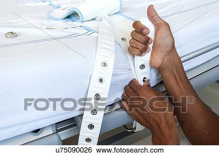 Stock Photograph - Nurse fastening medical restraint to hospital bed. Fotosearch
