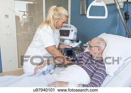 Stock Image - Nurse taking senior man's blood pressure. Fotosearch