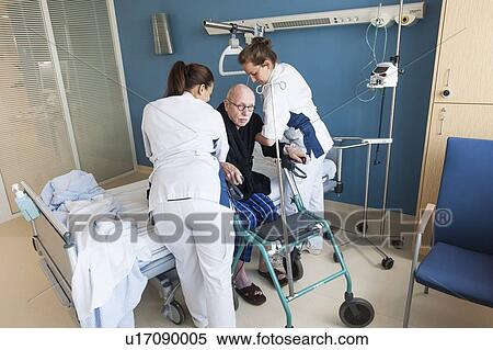 Stock Photography - Nurses helping senior male to sit down. Fotosearch