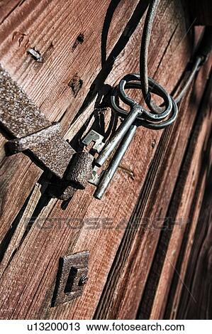 Stock Image - Old metal keys on wooden door. Fotosearch