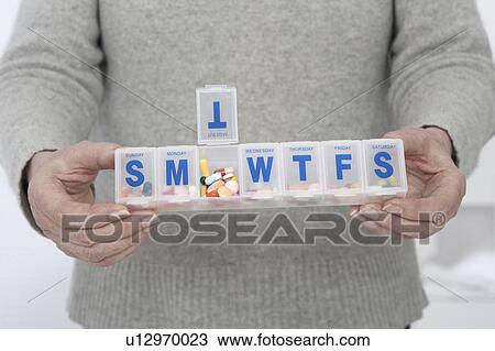 Stock Image - Person holding pill organiser. Fotosearch