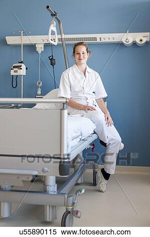 Stock Photography - Portrait of nurse sitting on hospital bed. Fotosearch