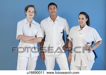 Stock Image - Portrait of three nurses against blue background. Fotosearch