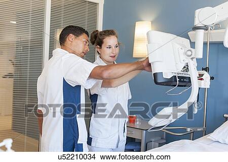 Two nurses checking monitor on hospital bed View Large Photo Image Picture - Two nurses checking monitor on hospital bed. Fotosearch