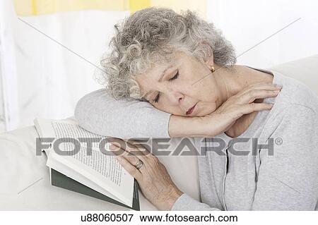 Stock Photo - Woman asleep on book on sofa. Fotosearch