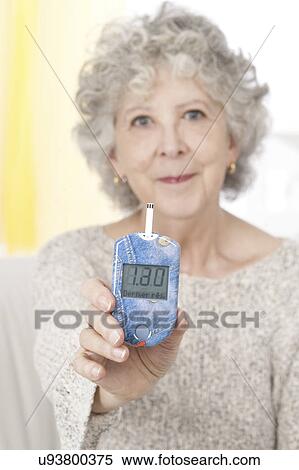 Stock Photography - Woman holding glucometer. Fotosearch
