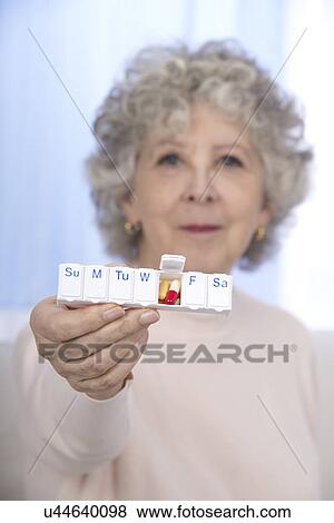Stock Photo - Woman holding pill organiser. Fotosearch