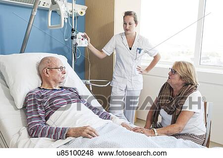 Stock Photo - Woman visiting senior man, nurse listening. Fotosearch
