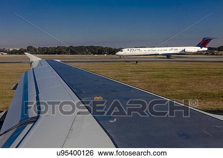 Stock Photograph - Airplane wing view of plane taking off from airport. Fotosearch