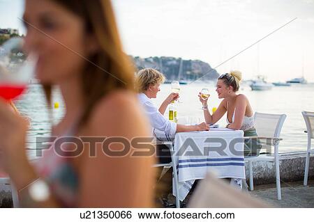 Stock Photograph - Background view of young couple at waterfront restaurant, Majorca, Spain. Fotosearch