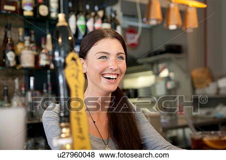Stock Photo - Bartender serving drinks in pub, London. Fotosearch