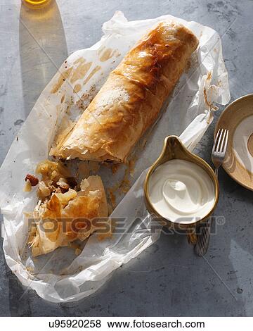 Stock Photo - Bistro dessert of apple strudel and cream on table. Fotosearch