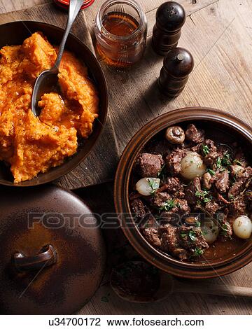 Stock Image - Bistro meal of beef burgundy in casserole dish on table. Fotosearch
