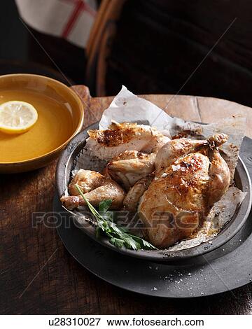 Stock Photo - Bistro meal of roast chicken in a basket with parsley on table. Fotosearch