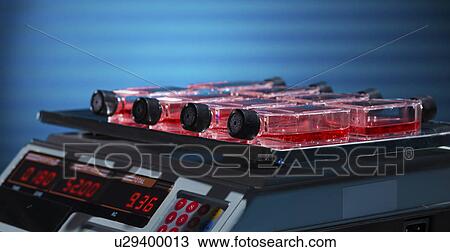 Stock Image - Bottles containing liquid on a laboratory shaker. Fotosearch