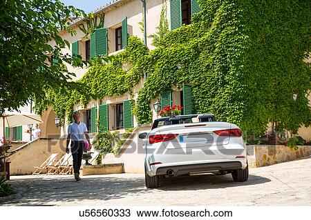 Boutique hotel porter welcoming couple arriving in convertible, Majorca, Spain View Large Photo Image Stock Image - Boutique hotel porter welcoming couple arriving in convertible, Majorca, Spain. Fotosearch