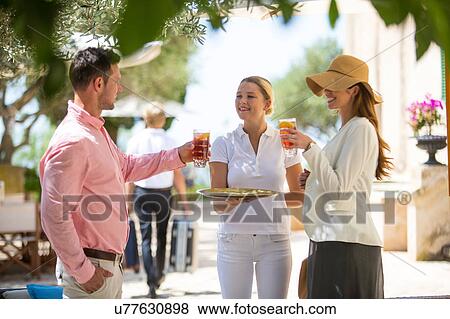 Stock Photo - Boutique hotel waitress welcoming couple with drinks, Majorca, Spain. Fotosearch