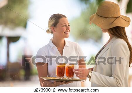 Boutique hotel waitress welcoming young woman with drinks, Majorca, Spain View Large Photo Image Stock Image - Boutique hotel waitress welcoming young woman with drinks, Majorca, Spain. Fotosearch