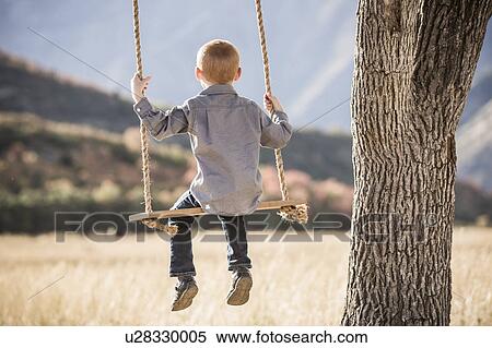Boy (4-5) sitting on swing View Large Photo Image Stock Photography - Boy (4-5) sitting on swing. Fotosearch