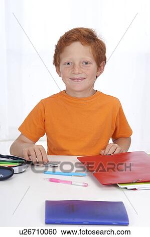 Stock Image - Boy doing homework, smiling. Fotosearch