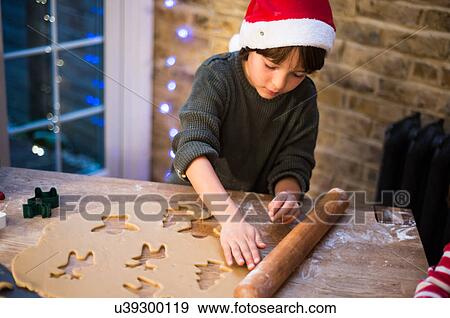 Stock Photo - Boy in Santa hat preparing Christmas cookies at kitchen counter. Fotosearch