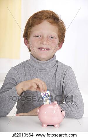 Boy putting money in piggy bank View Large Photo Image Picture - Boy putting money in piggy bank. Fotosearch