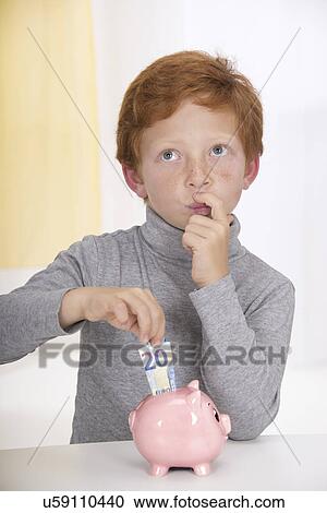 Boy putting money in piggy bank View Large Photo Image Stock Image - Boy putting money in piggy bank. Fotosearch