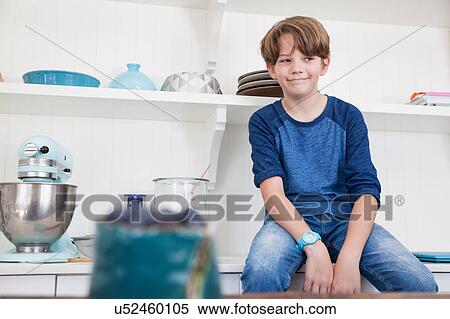 Stock Photography - Boy sitting on kitchen work surface. Fotosearch