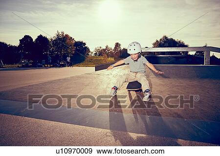 Boy sitting on skateboard in park View Large Photo Image Stock Photo - Boy sitting on skateboard in park. Fotosearch