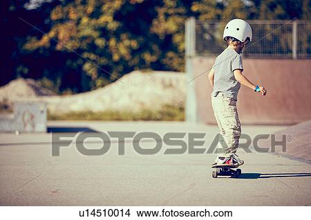 Picture - Boy skateboarding in park. Fotosearch