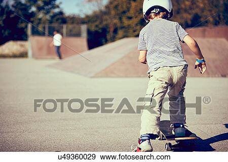 Boy skateboarding in park View Large Photo Image Stock Photo - Boy skateboarding in park. Fotosearch