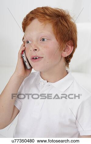 Stock Image - Boy using cell phone, looking away. Fotosearch