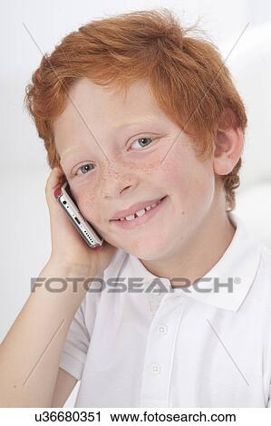 Stock Image - Boy using cell phone, smiling. Fotosearch