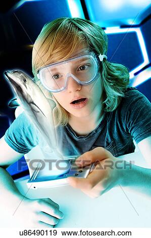 Stock Photo - Boy with hand held computer staring at digital jumping dolphin. Fotosearch