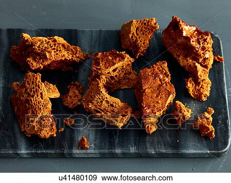 Stock Photo - Broken honeycomb toffee on marble cutting board. Fotosearch