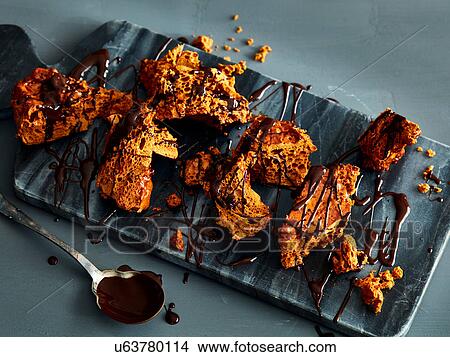 Broken honeycomb toffee with melted chocolate garnish on marble cutting board View Large Photo Image Picture - Broken honeycomb toffee with melted chocolate garnish on marble cutting board. Fotosearch