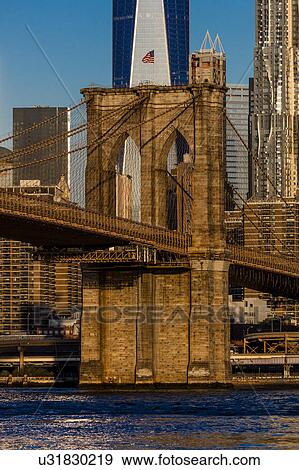 Stock Photo - Brooklyn Bridge and Manhattan Skyline features One World Trade Center at Sunrise, NY NY. Fotosearch