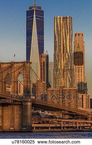 Stock Photography - Brooklyn Bridge and Manhattan Skyline features One World Trade Center at Sunrise, NY NY. Fotosearch