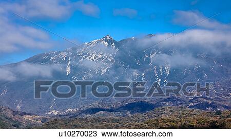 Stock Image - Clouds go by mountain top in Ojai California. Fotosearch