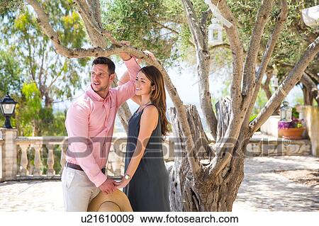 Couple by olive tree in boutique hotel garden, Majorca, Spain View Large Photo Image Stock Photo - Couple by olive tree in boutique hotel garden, Majorca, Spain. Fotosearch