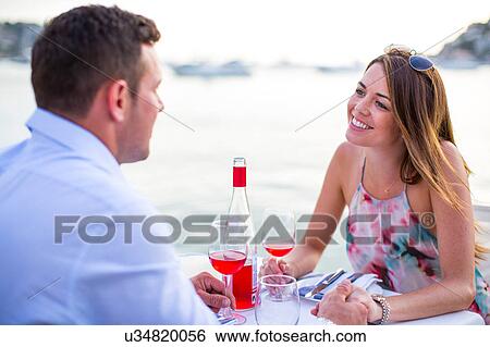 Stock Photograph - Couple chatting at waterfront restaurant, Majorca, Spain. Fotosearch