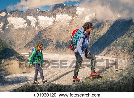 Stock Image - Couple climbing up ridge over Aletsch Glacier, Canton Wallis, Switzerland. Fotosearch