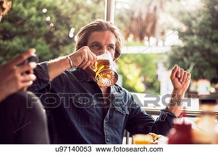 Stock Image - Couple drinking beer at sidewalk cafe, Cape Town, South Africa. Fotosearch