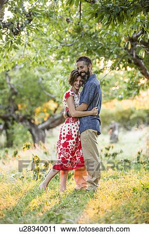 Stock Image - Couple embracing in cherry orchard. Fotosearch