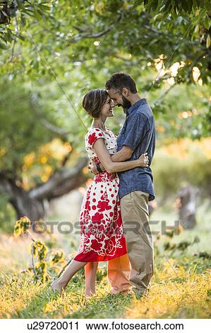 Stock Image - Couple embracing in cherry orchard. Fotosearch